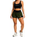 Mulher vestindo conjunto fitness preto e verde, top esportivo e shorts, ideal para treino.
