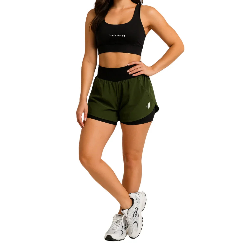 Mulher usando top fitness preto e shorts esportivo verde e preto, moda activewear.